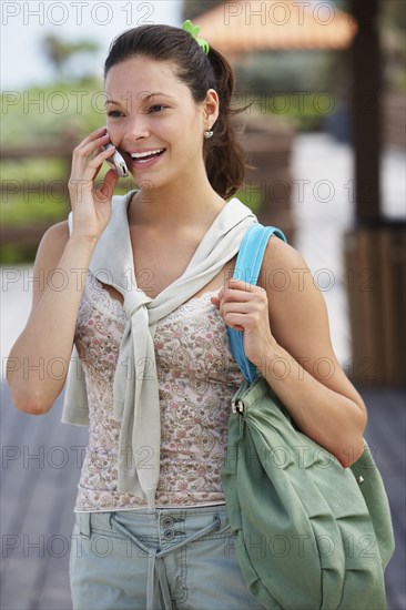 Hispanic woman talking on cell phone on boardwalk