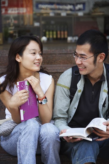 Young Asian couple holding school books