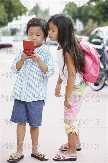 Asian brother and sister playing with handheld game