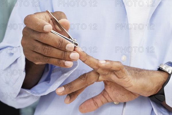 African American man clipping fingernails