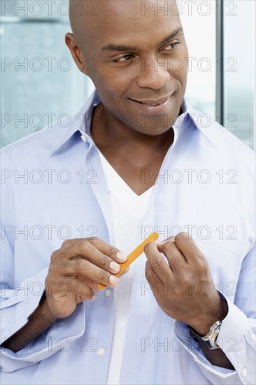 African American man filing fingernails