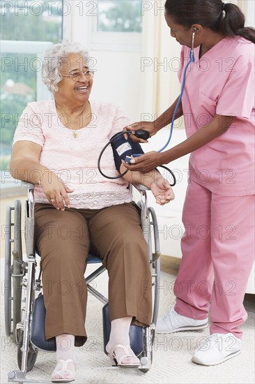 Nurse taking senior woman's blood pressure