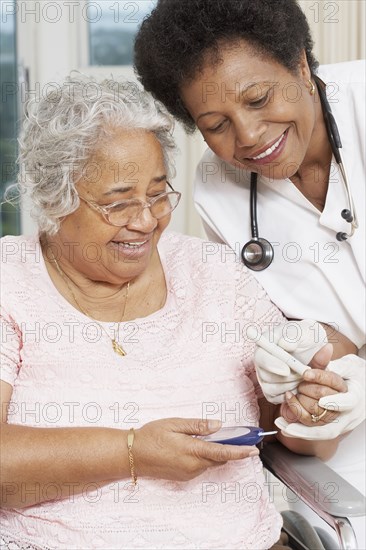 Doctor testing African American woman's blood sugar