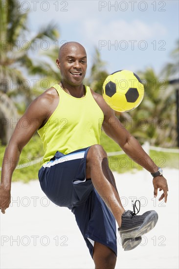 African American man bouncing soccer ball on knee