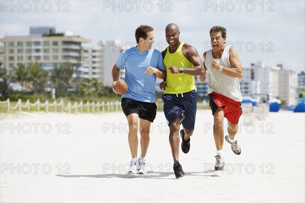 Multi-ethnic men running in beach