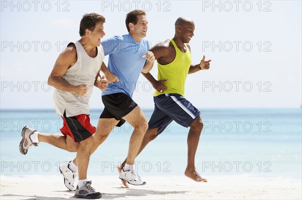 Multi-ethnic men running in beach