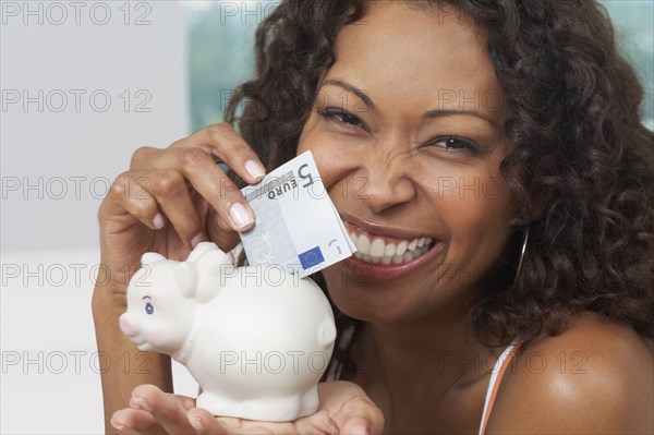 African woman putting money in piggyback