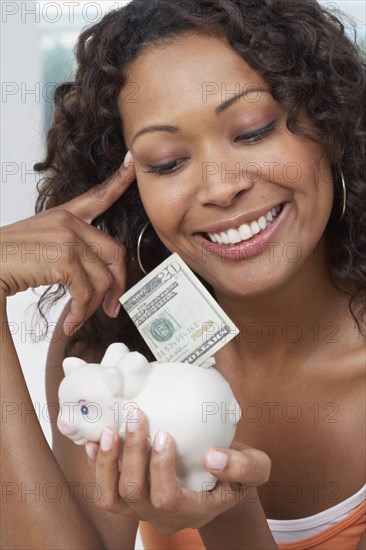 African woman putting money in piggyback