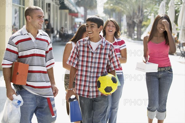 Multi-ethnic teenagers walking on sidewalk