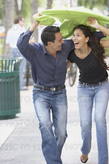 Couple holding raincoat over heads