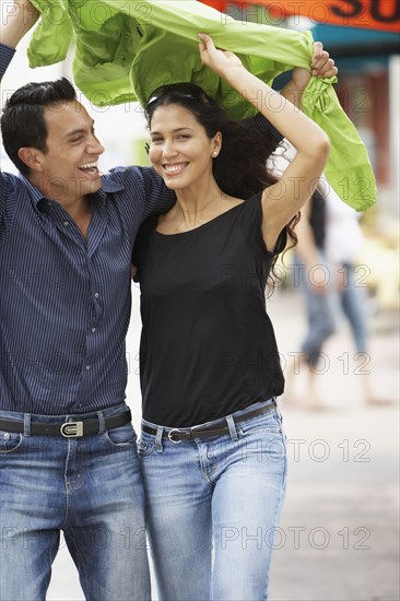 Couple holding raincoat over heads