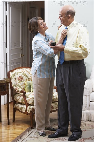 Senior Hispanic woman adjusting husband's necktie