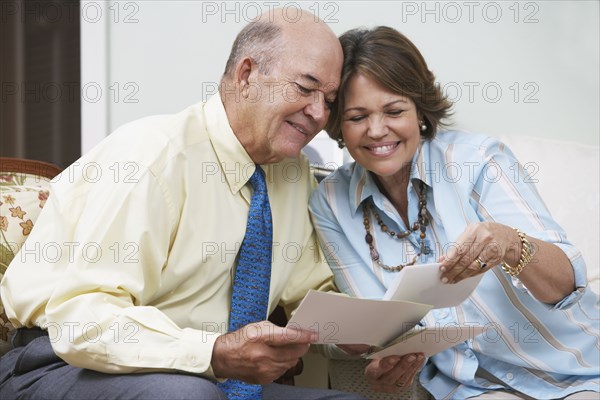 Senior Hispanic couple looking at photographs