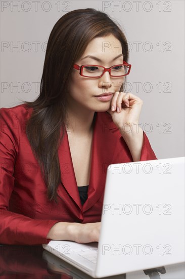 Asian businesswoman looking at laptop