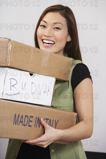 Asian woman carrying stack of packages