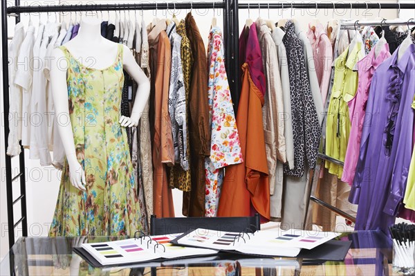 Textile swatches and mannequin in front of clothing rack