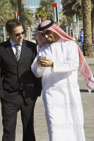 Multi-ethnic businessmen looking at cell phone