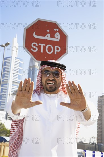 Arab man standing below stop sign