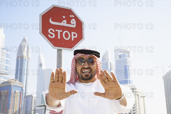 Arab man standing below stop sign