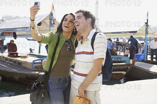 Multi-ethnic couple taking self-portrait at waterfront