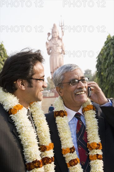 Indian businessmen wearing floral necklaces at tourist attraction