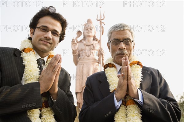 Indian businessmen wearing floral necklaces at tourist attraction