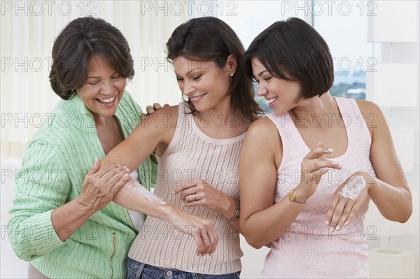 Mother and sisters applying lotion to skin