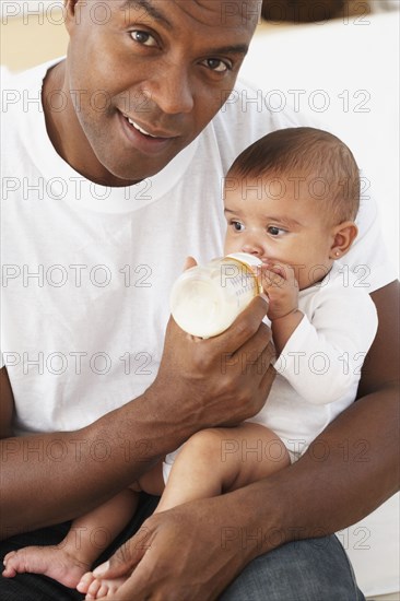 African father feeding baby daughter