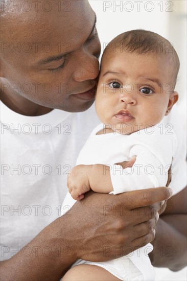 African father hugging baby daughter