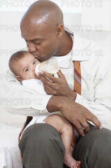 African father feeding baby daughter