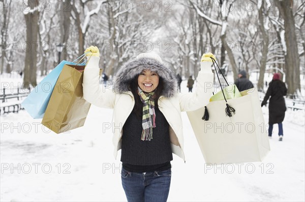 Korean woman in snowy park carrying shopping bags