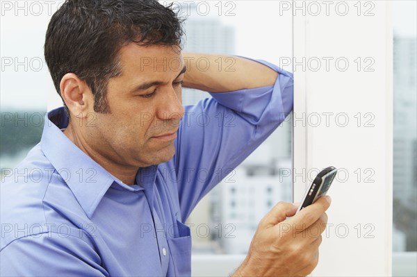 Hispanic businessman text messaging on cell phone