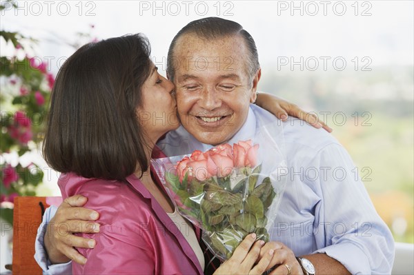 Hispanic man giving wife flowers