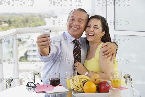 Hispanic couple taking self-portrait with cell phone