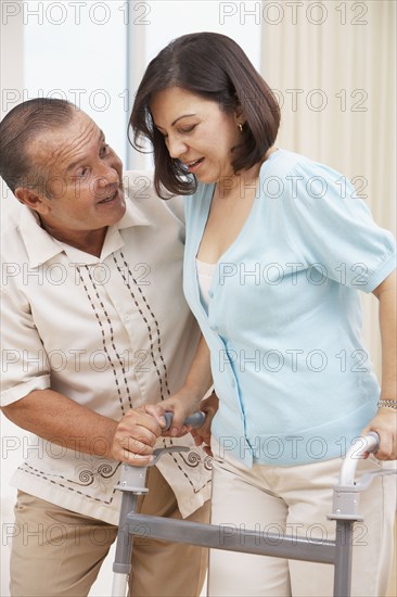 Hispanic man encouraging wife using walker