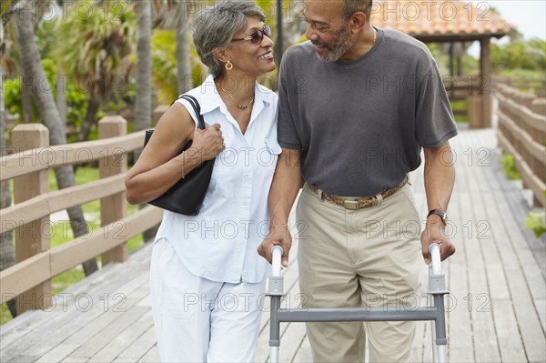 African woman walking with husband using walker