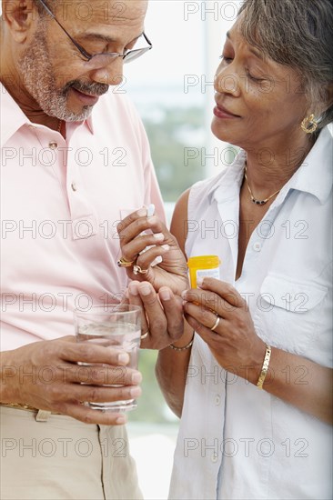 African woman helping husband take medication