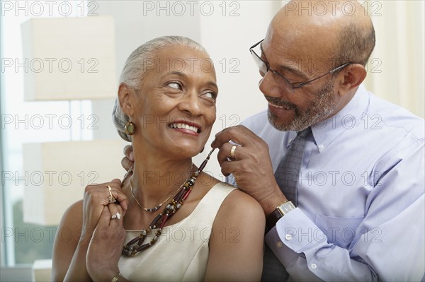 African man helping wife with necklace
