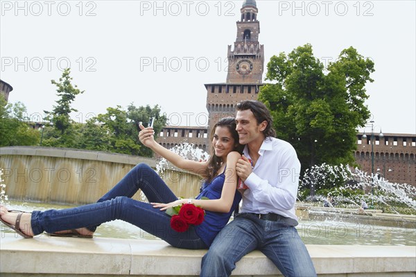 Couple taking self-portrait near fountain