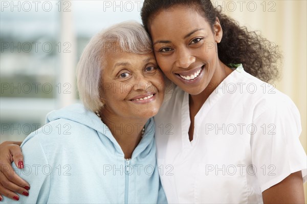 African American nurse hugging senior woman