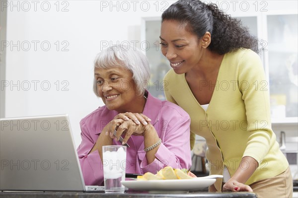 African American woman helping mother with laptop