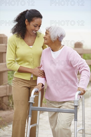 African American woman helping mother use walker