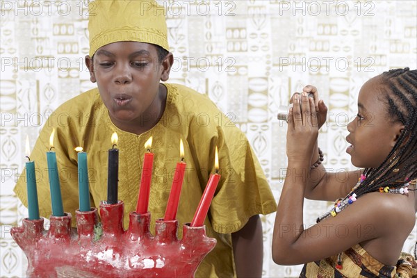 African American boy blowing out Kwanzaa candles