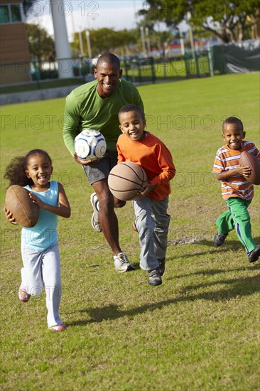 African American father playing ball with children