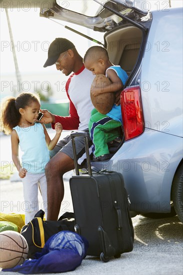 African American father holding cell phone for daughter