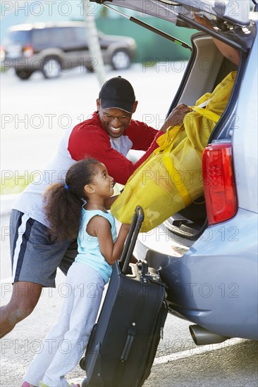 African American father and daughter loading car