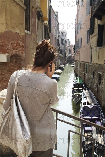 Italian woman talking on cell phone near canal