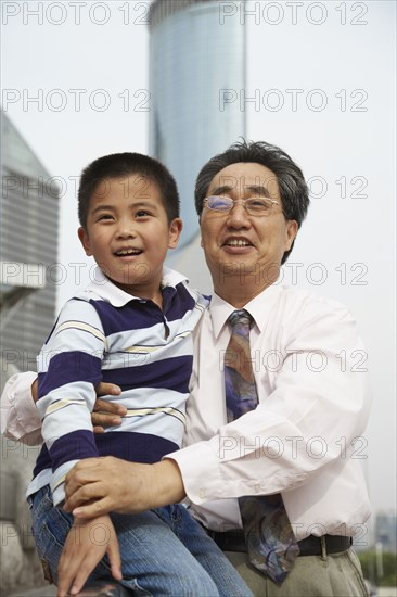 Chinese grandfather and grandson sitting together outdoors