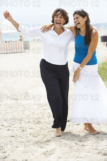 Hispanic mother and daughter laughing on beach