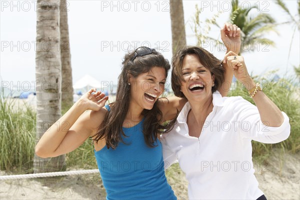 Hispanic mother and daughter laughing on beach